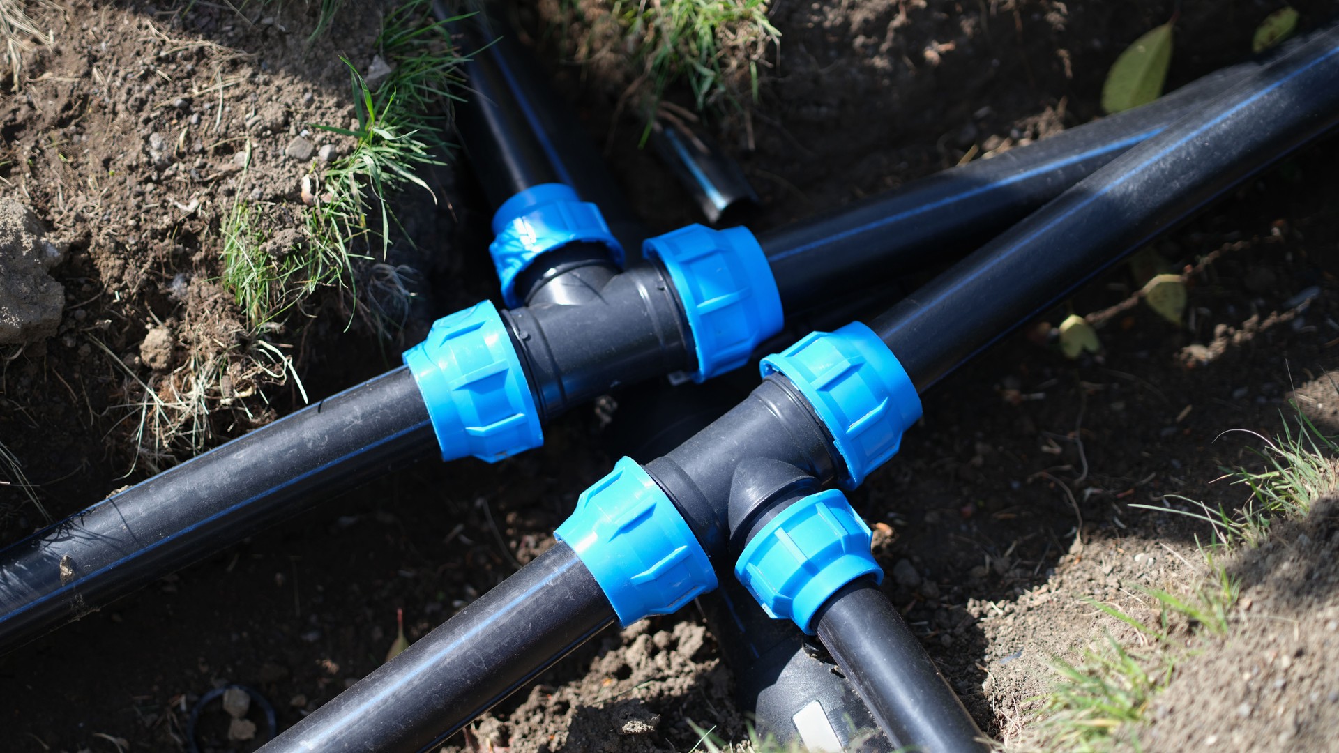 Black three way plastic water pipe on grass